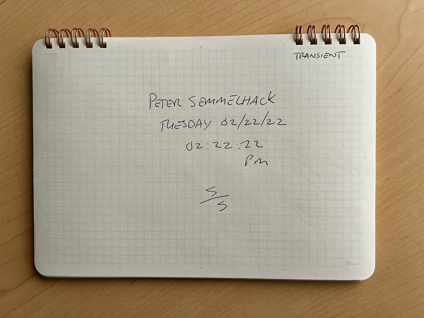 A grid notebook headed TRANSIENT, dated Tuesday 02/22/22, 02:22:22 PM, beside a tablet showing a clock and a map.